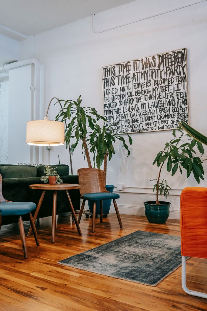 Contemporary interior of spacious light living room decorated painting on wall and potted tropical plants placed near modern wooden table and chairs